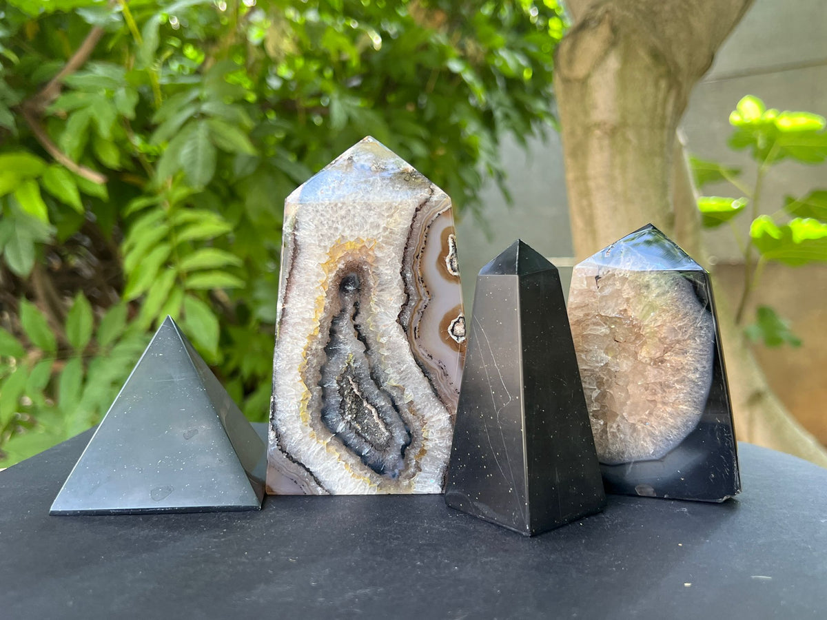 Cristale de onix negru în formă de piramidă și obelisc, alături de geode druzy – pietre semiprețioase pentru protecție și echilibru energetic